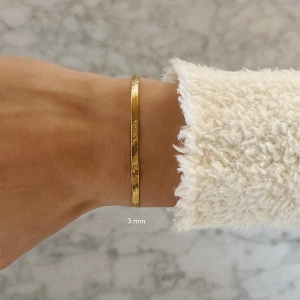 Pulseira dourada fina em braço com casaco felpudo branco