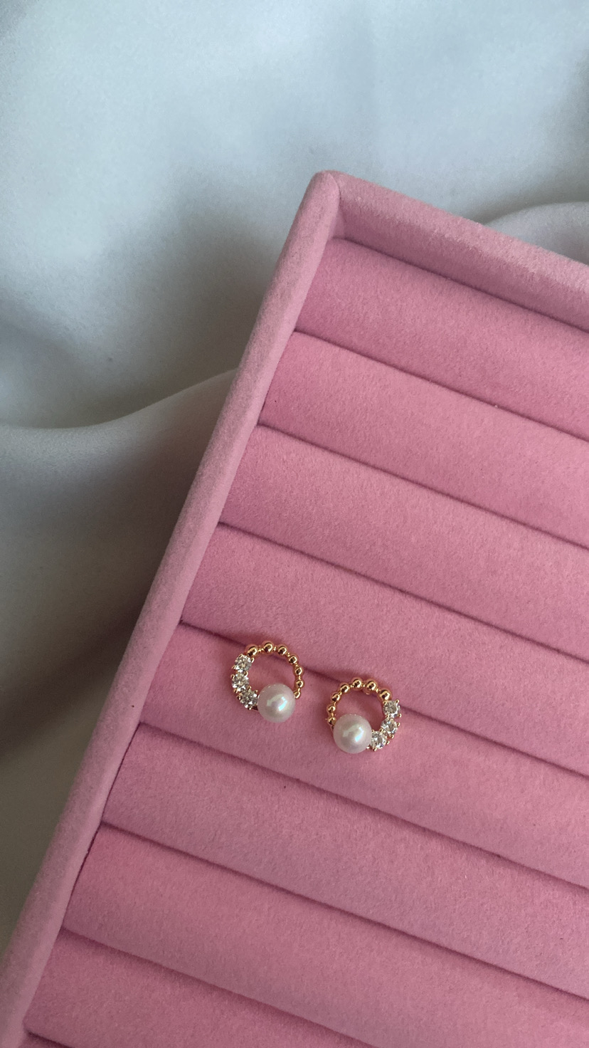 Brincos dourados com pérola e cristais numa caixa rosa de veludo