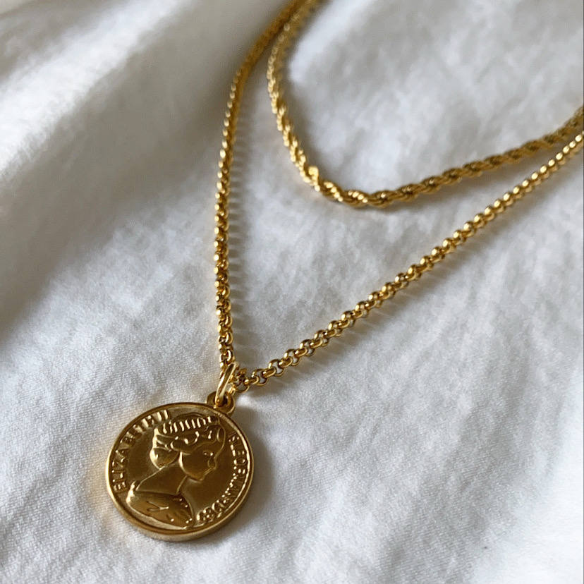 Colar dourado com pendente redondo e relevo de perfil com coroa