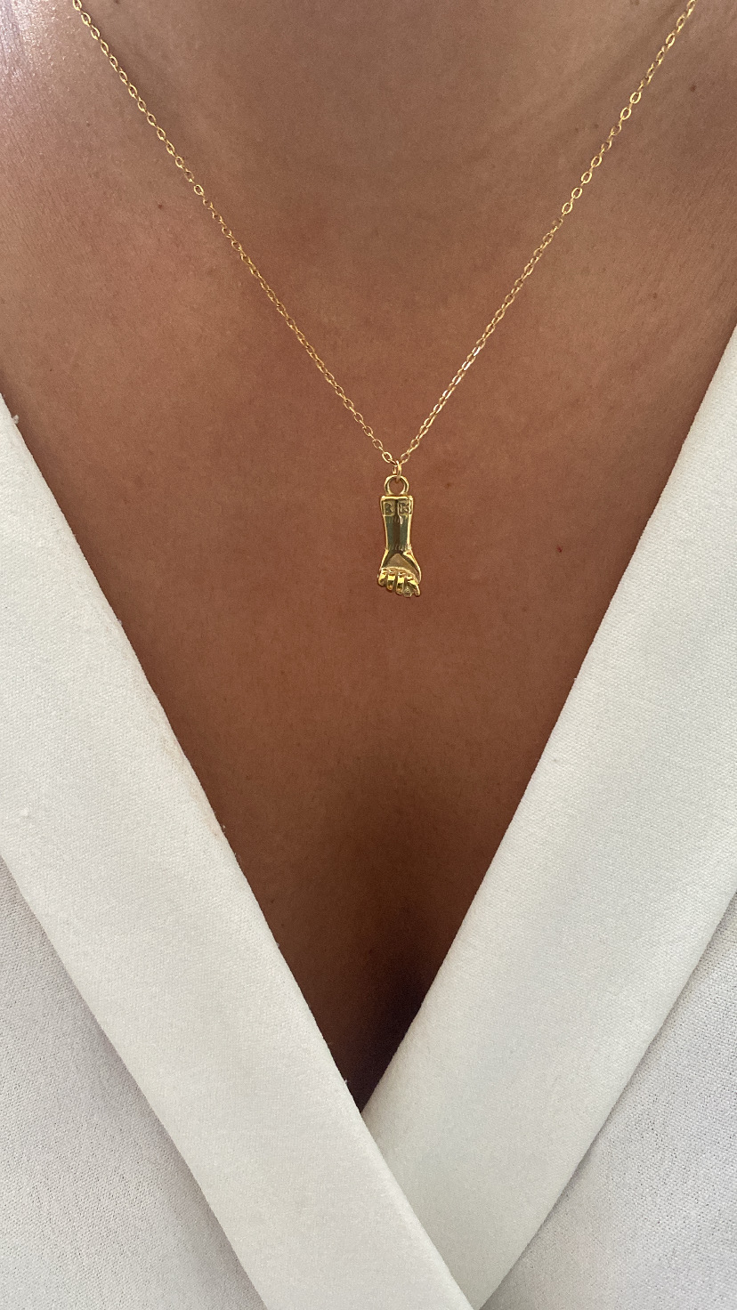 Colar dourado com pendente em forma de punho aberto