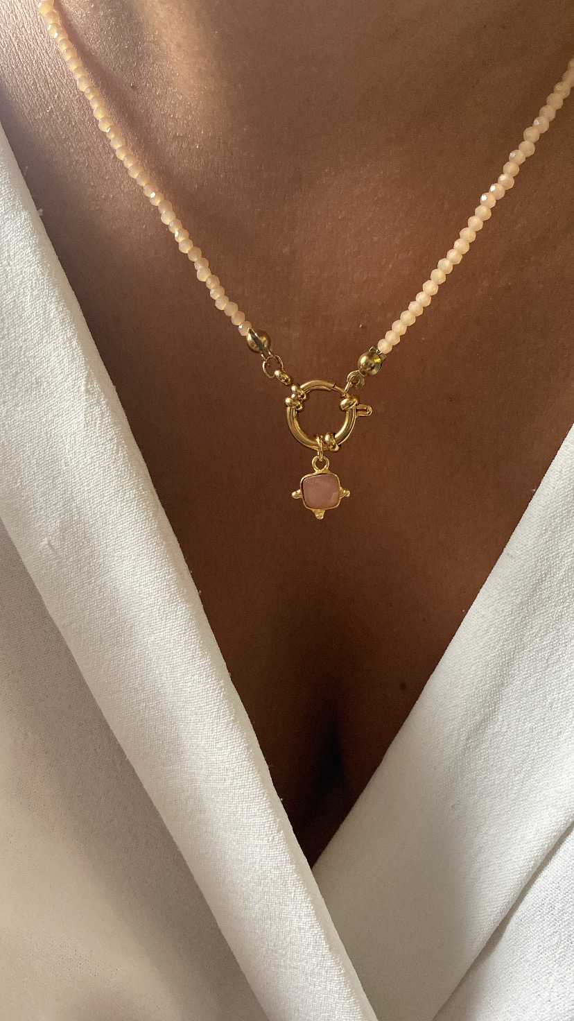 Colar rosa com pendente dourado em cruz e vestido branco