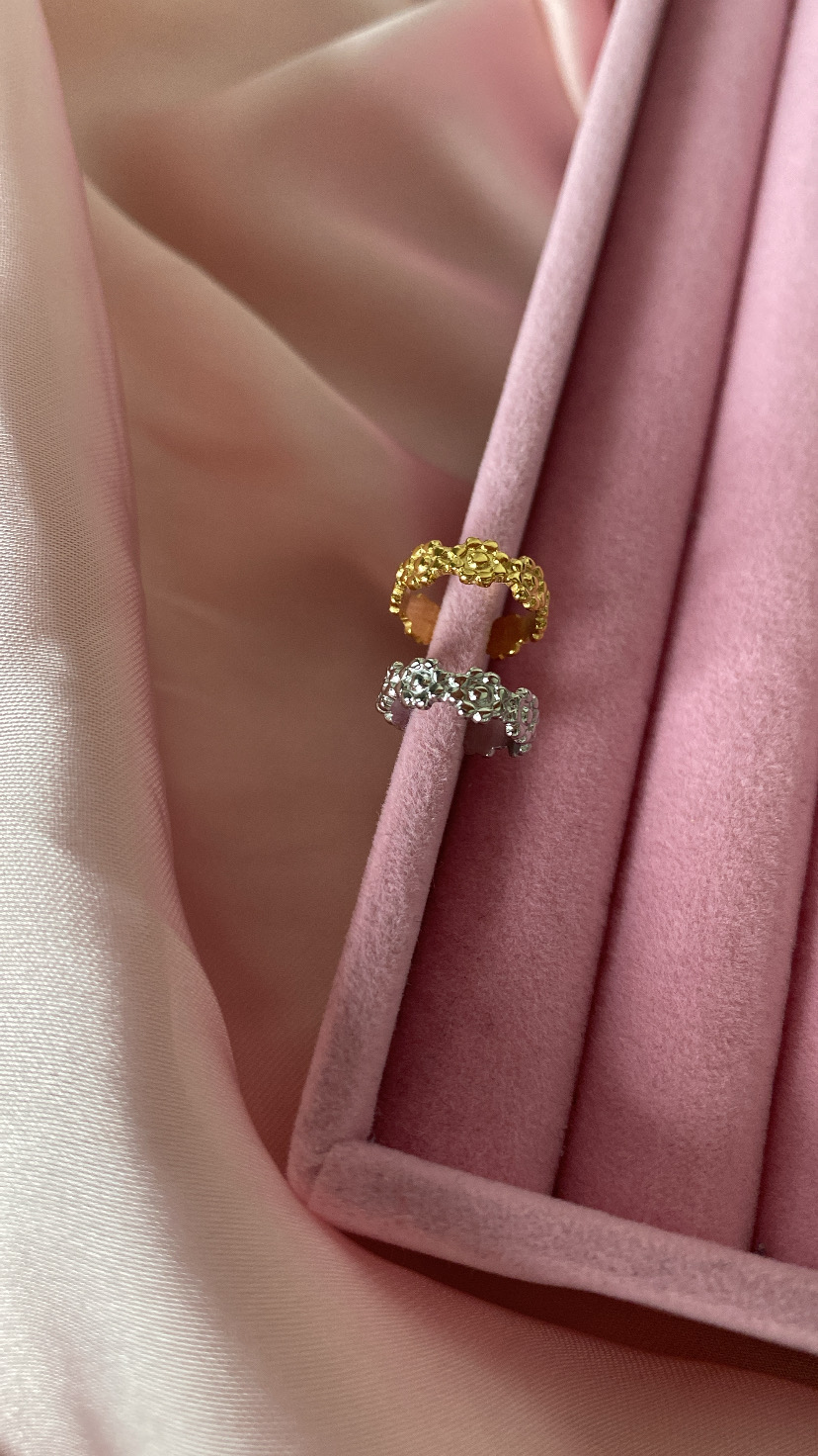 Dois anéis texturizados dourado e prateado num suporte de veludo rosa