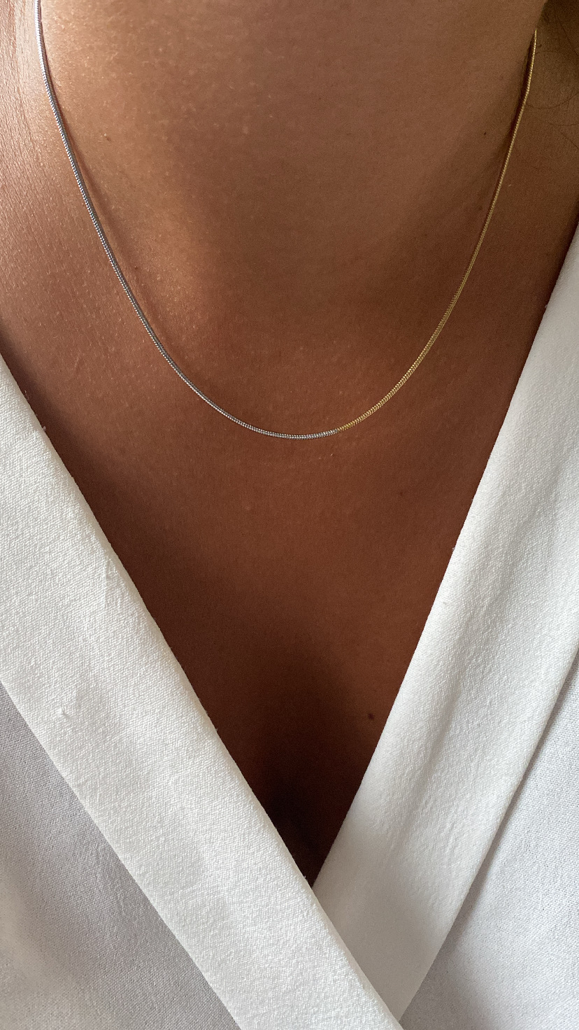 Colar bicolor fino num tecido branco