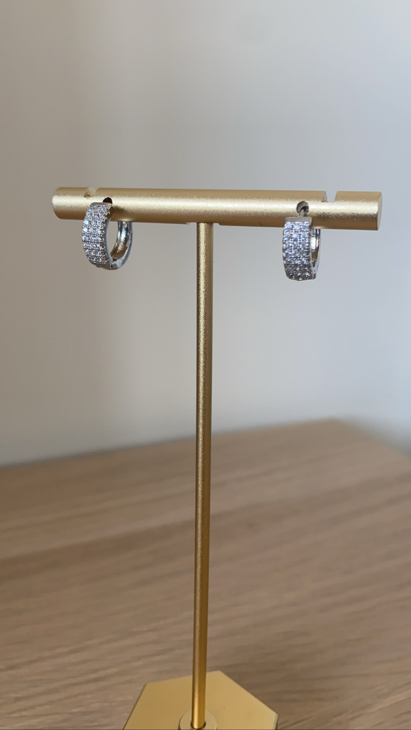 Brincos de argola prateados com pedras brilhantes em suporte dourado