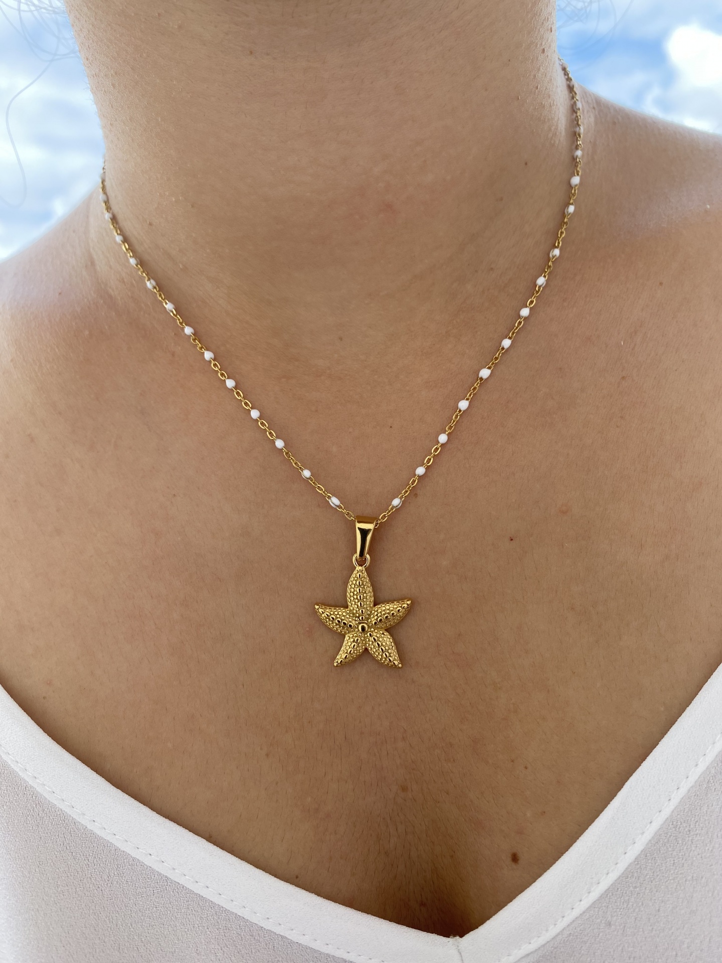 Colar dourado com pendente de estrela do mar texturizada e corrente com contas brancas