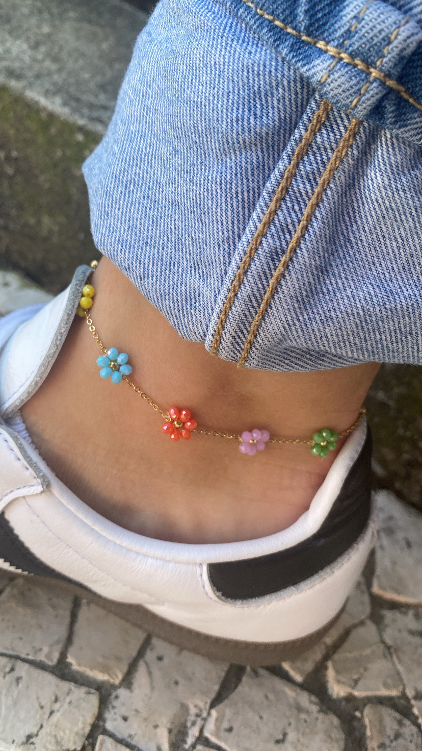 Tornozeleira colorida com flores em tornozelo junto a ténis e calça de ganga