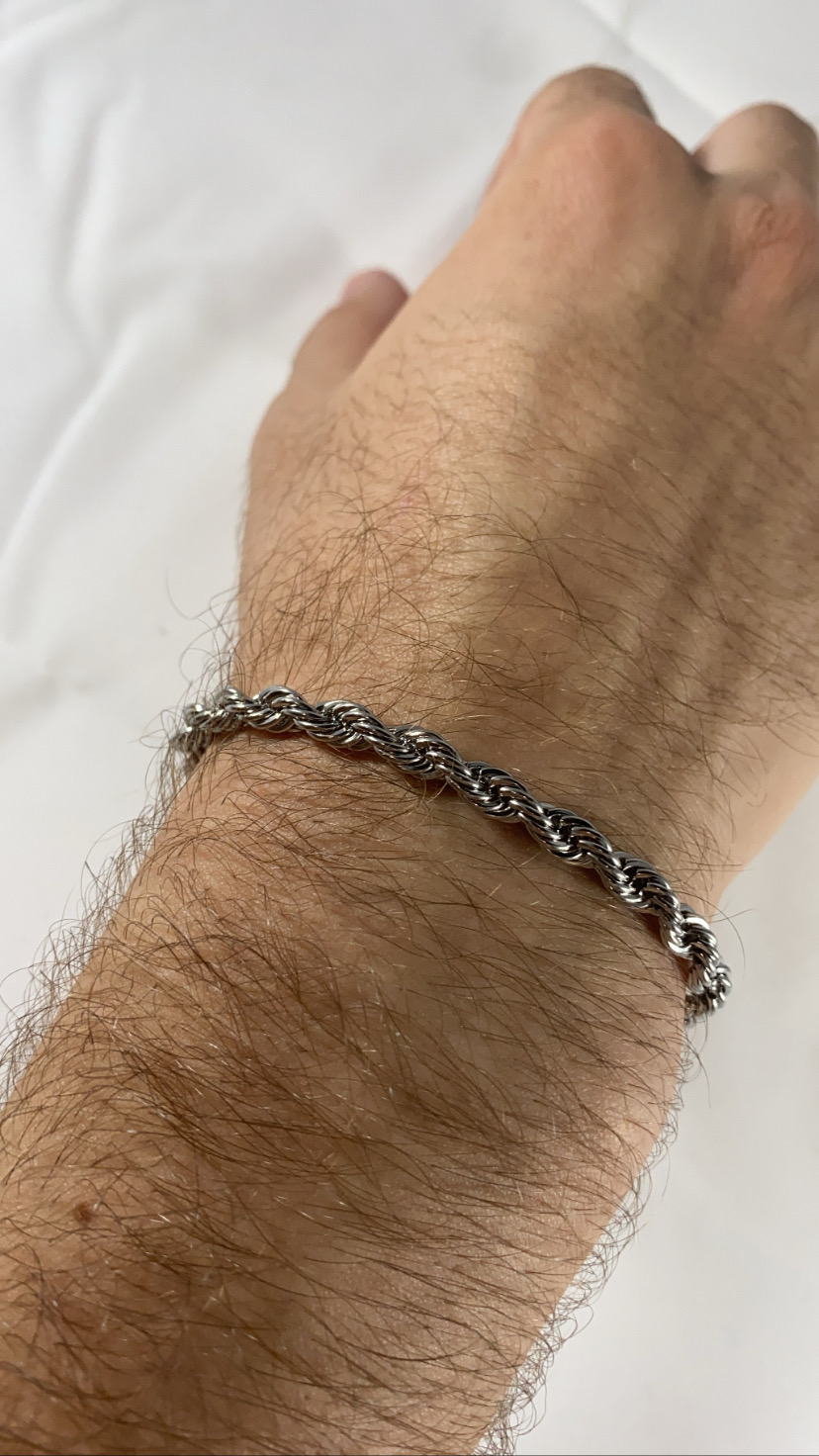 Pulseira prateada espiral no pulso de um braço peludo