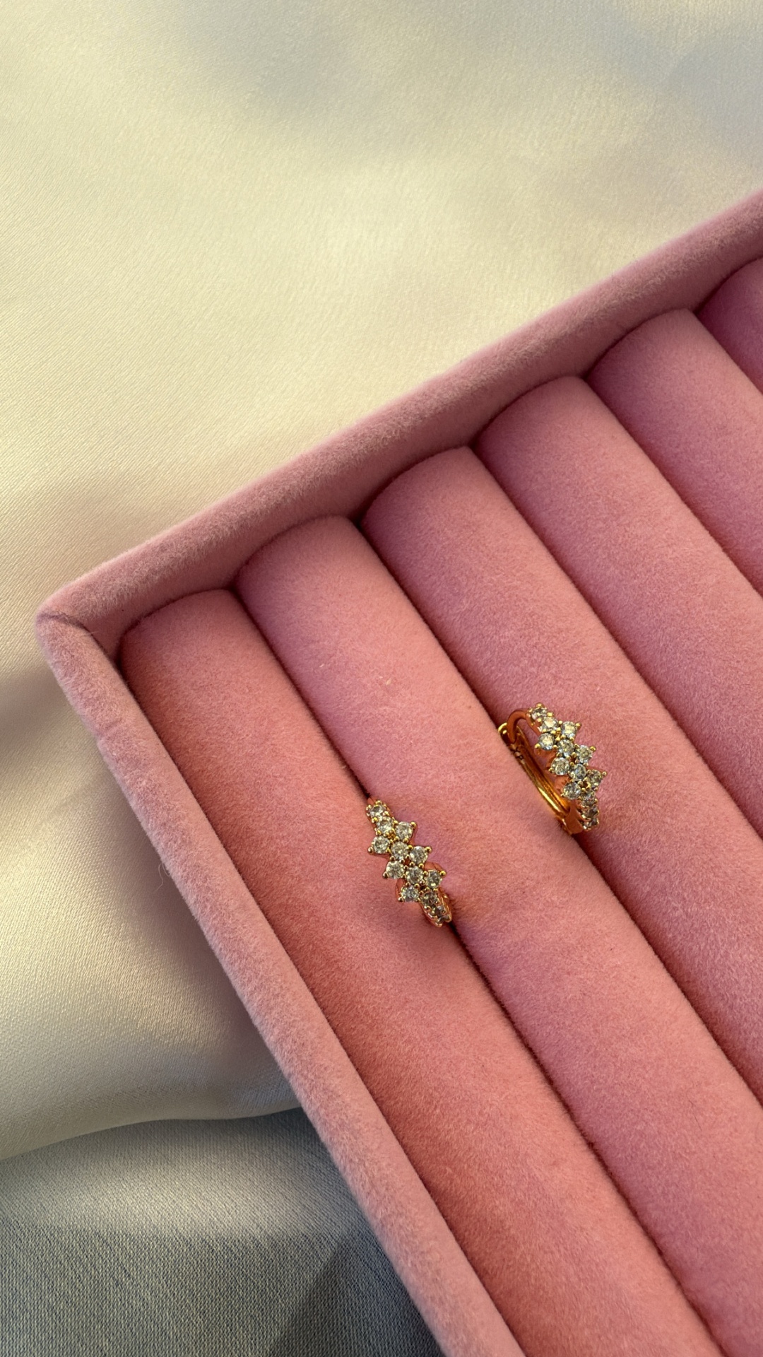 Brincos dourados com pedras brilhantes em caixa almofadada cor-de-rosa