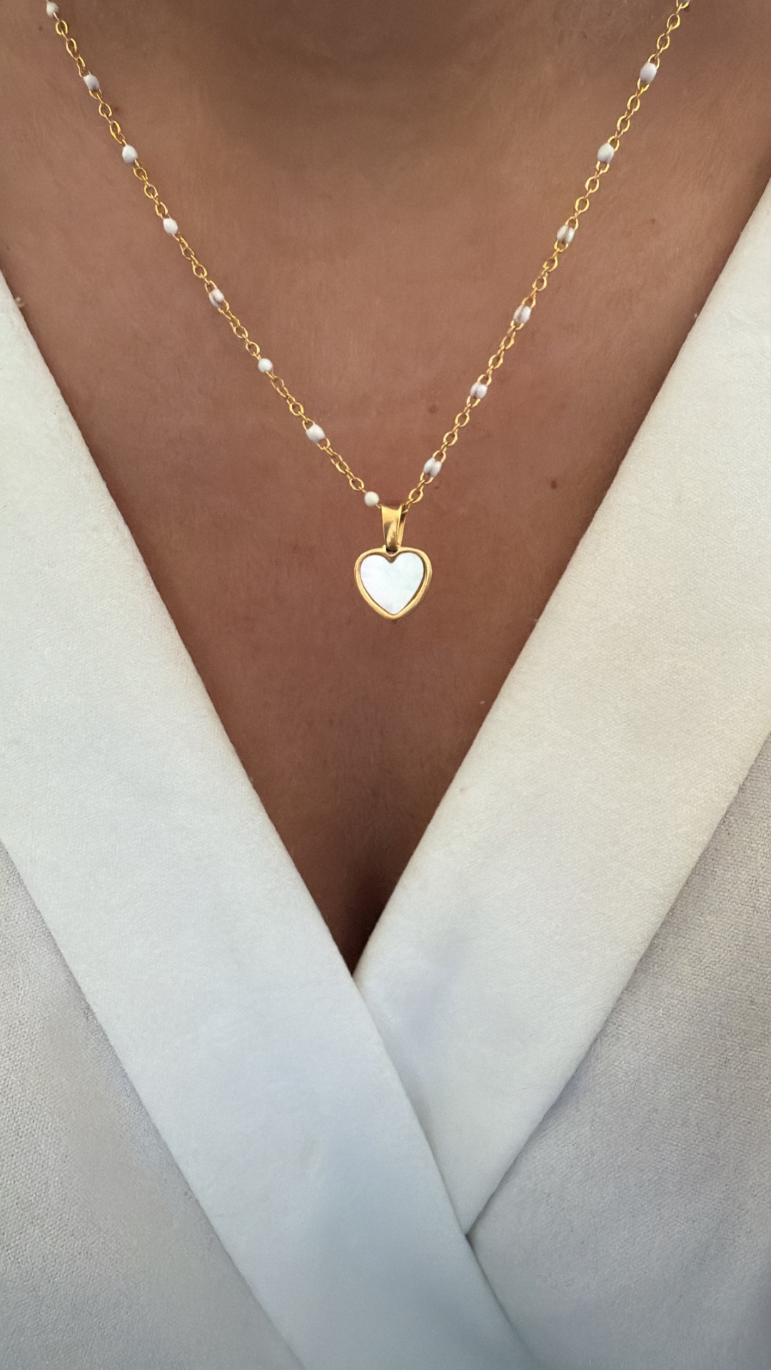 Colar dourado com pendente de coração branco