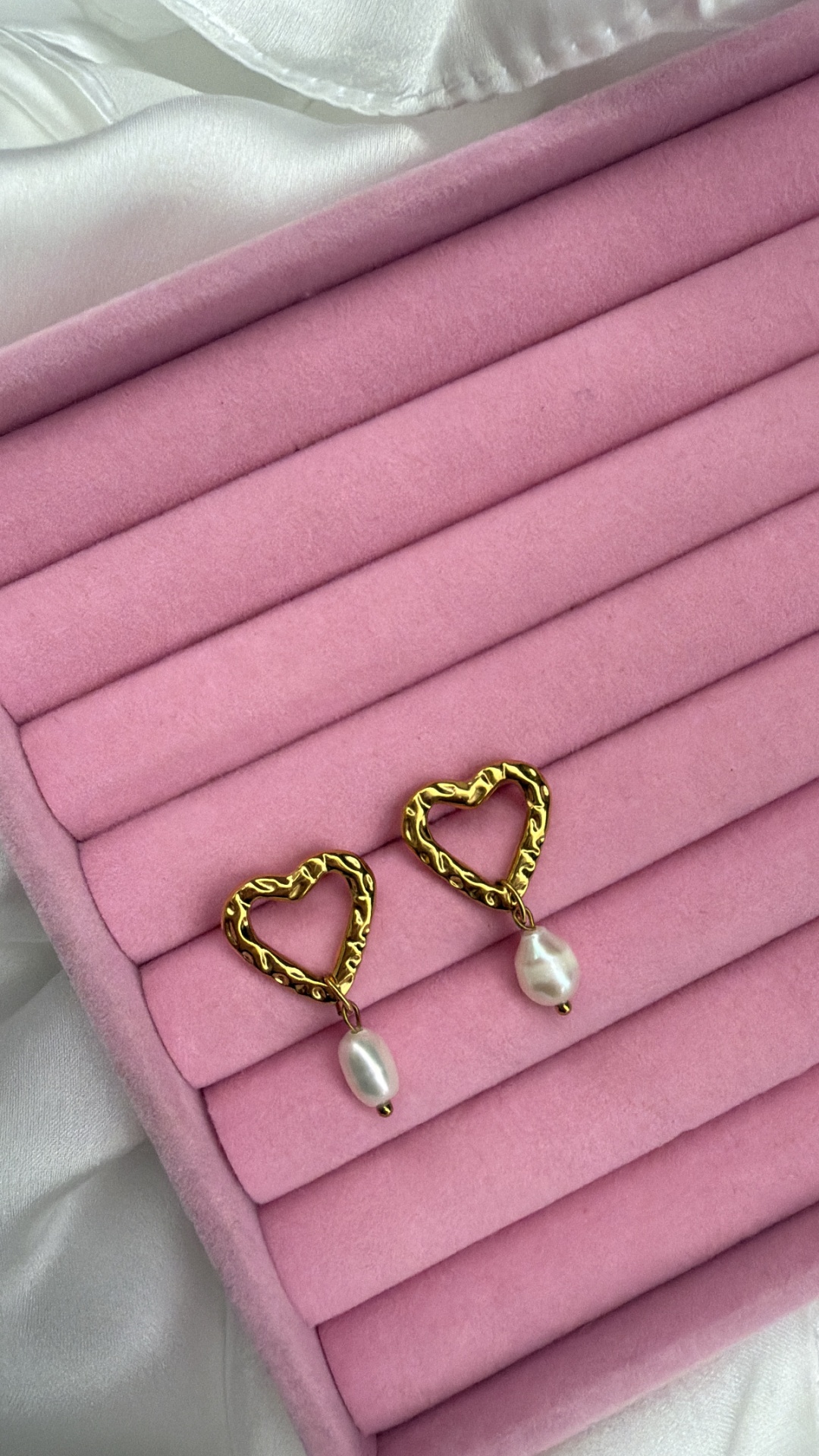 Brincos dourados em forma de coração com pérola pendente em caixa rosa