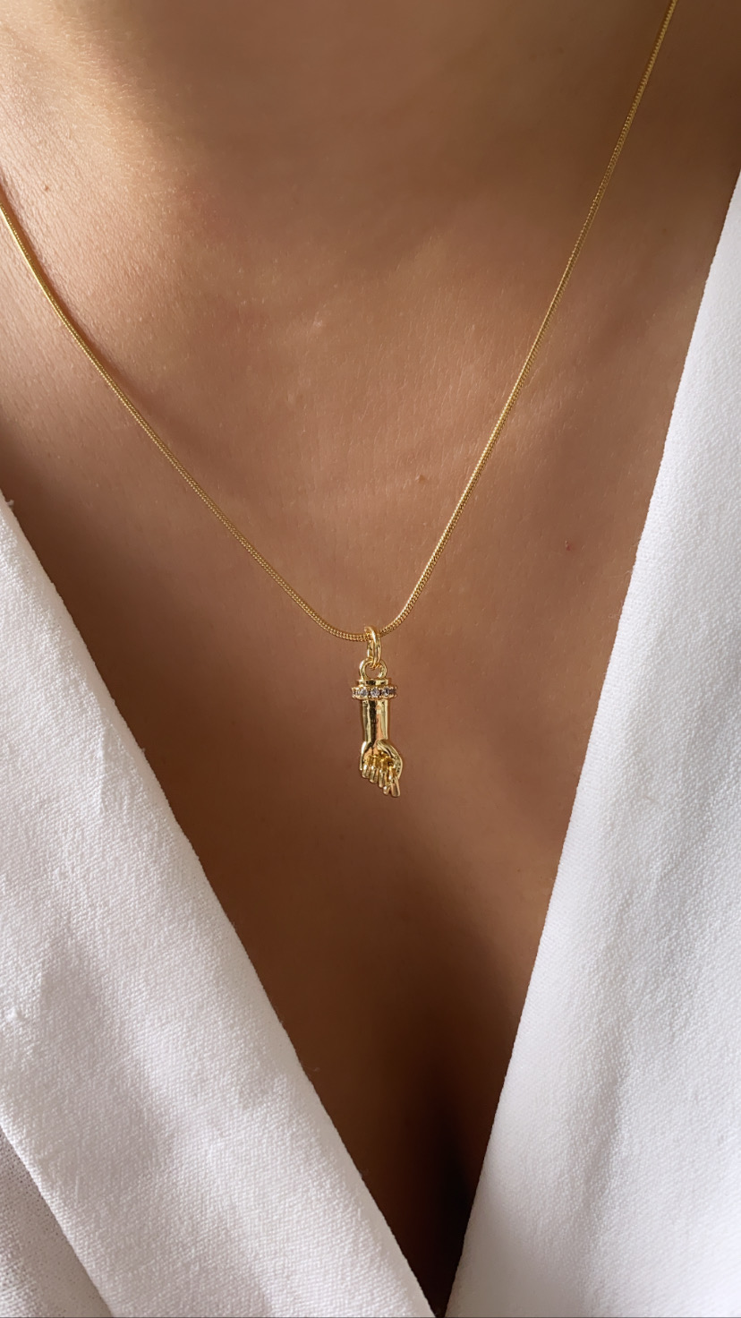 Colar dourado com pendente de mão e chave