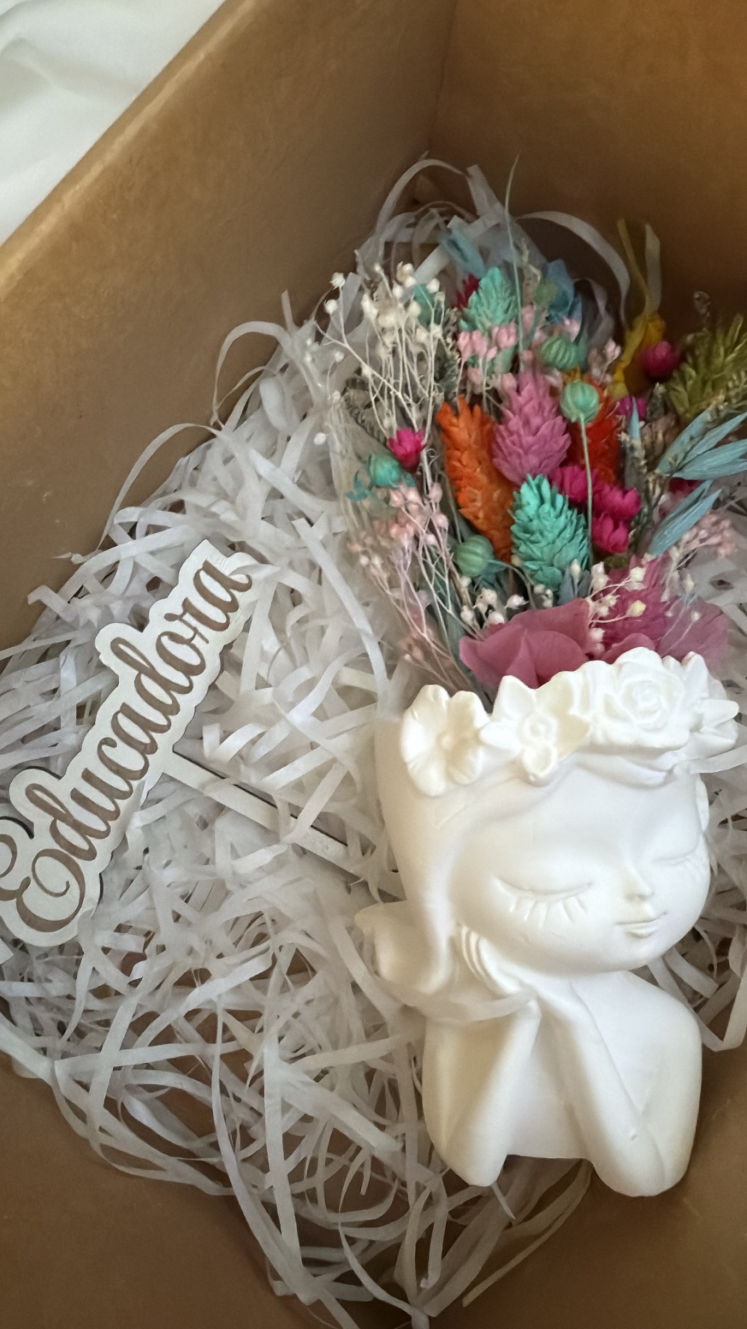 Vaso decorativo rosto branco com flores secas coloridas numa caixa de cartão