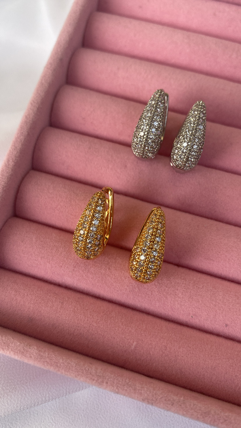 Dois pares de brincos em forma de gota com brilhantes num suporte de veludo rosa