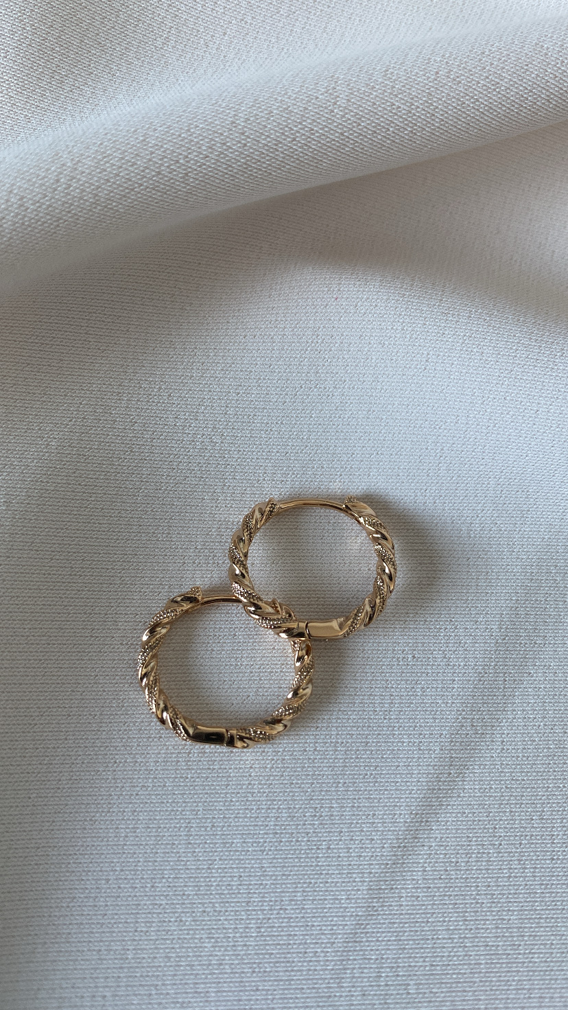 Brincos de argola dourados com textura torcida sobre fundo branco