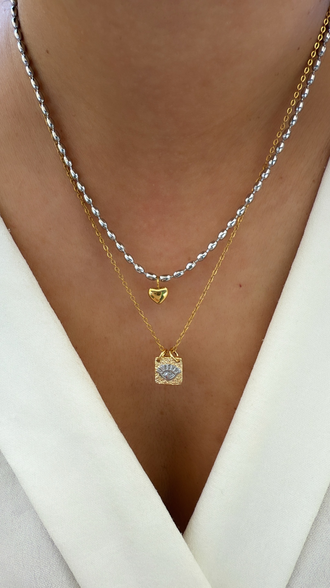 Colar duplo com pingentes em forma de coração e retângulo com olho azul.