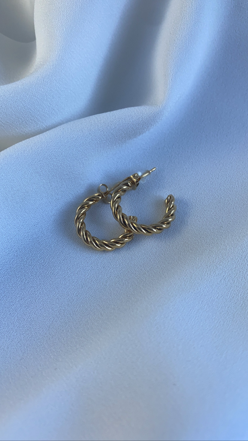 Brincos de argola dourados torcidos sobre tecido branco