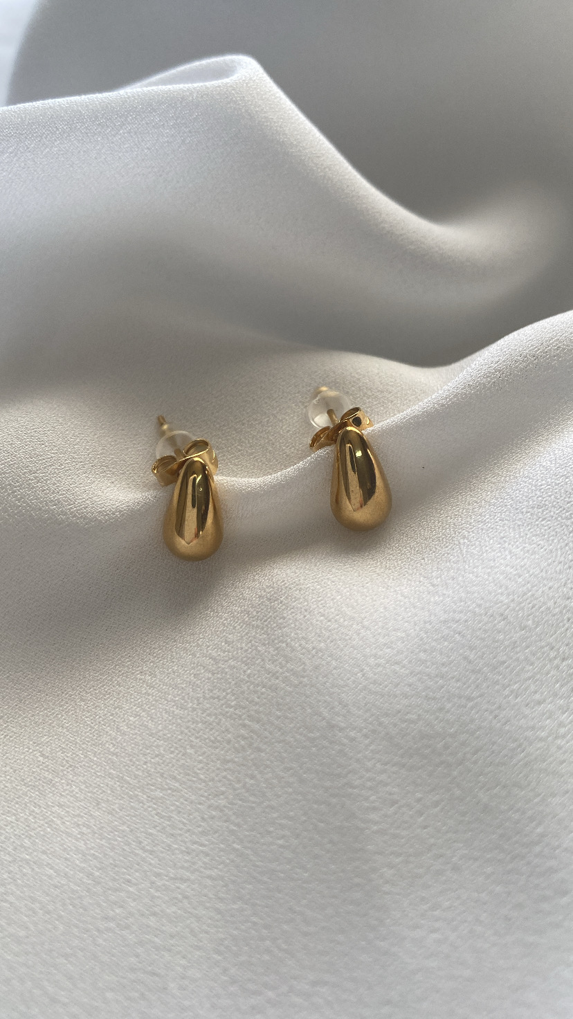 Brincos dourados pequenos sobre tecido branco
