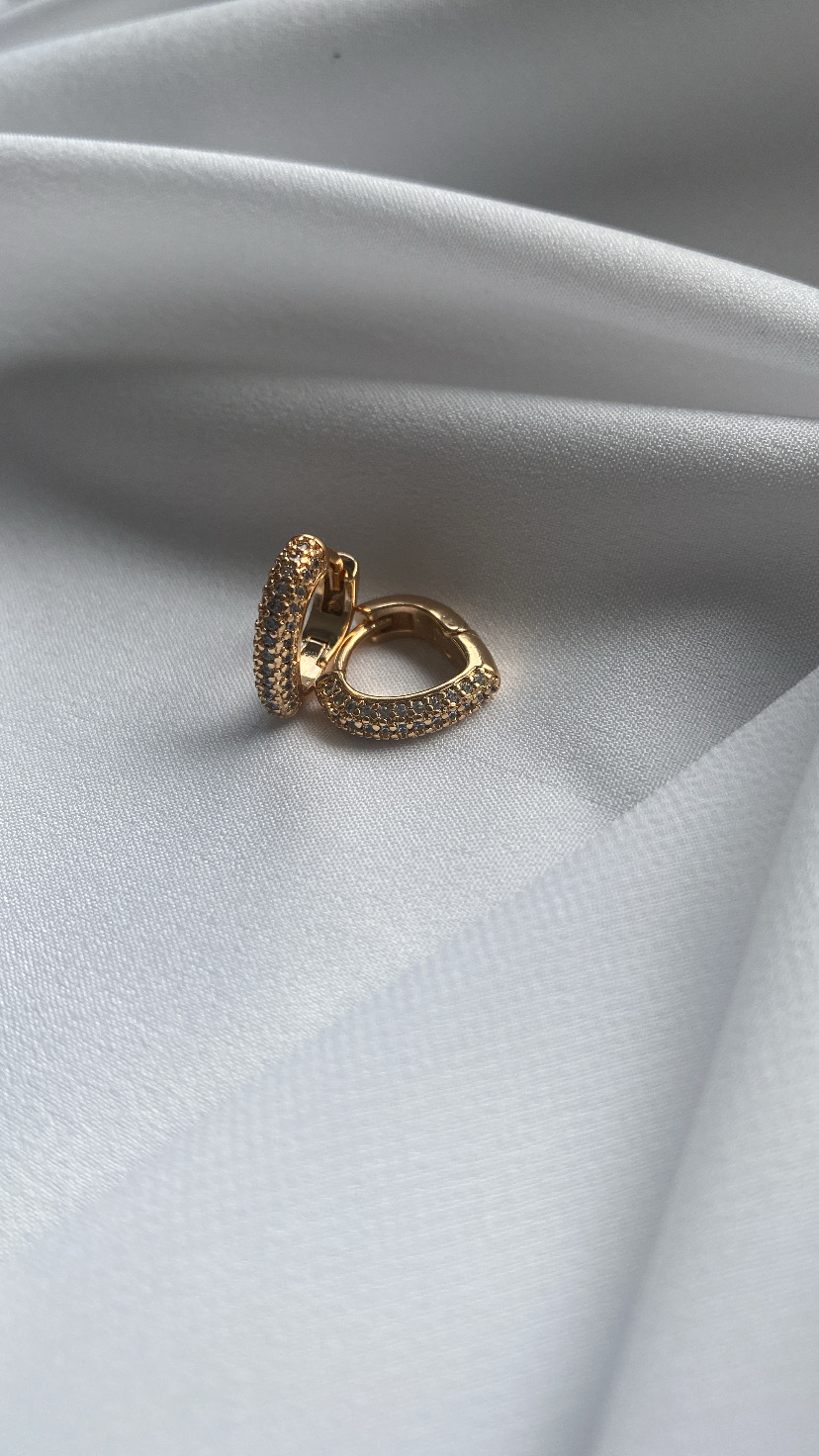 Brincos dourados com cristais sobre tecido branco