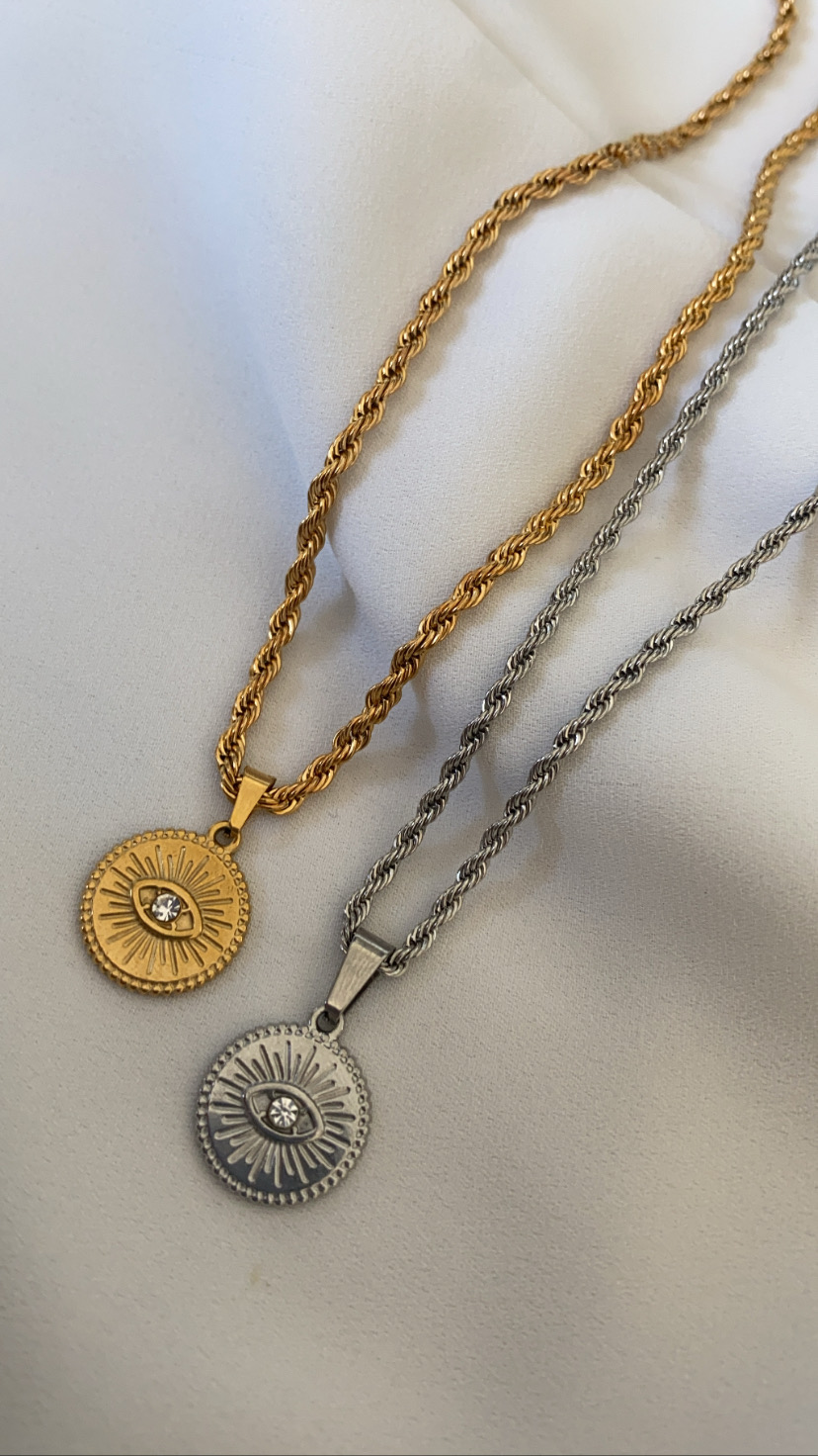 Dois colares com pendentes redondos dourado e prateado sobre tecido branco