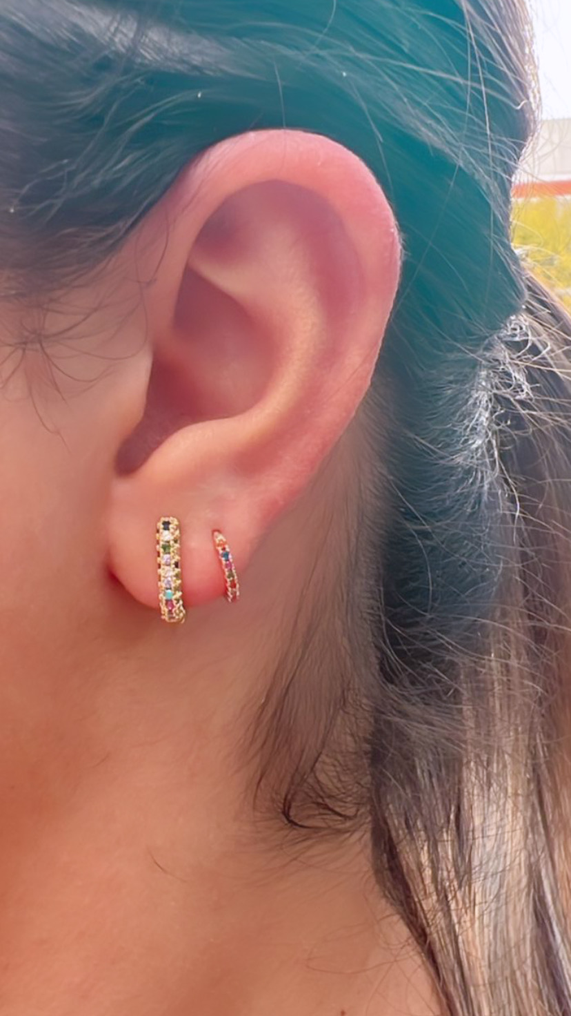 Orelha com dois brincos de argola dourados com pedras coloridas