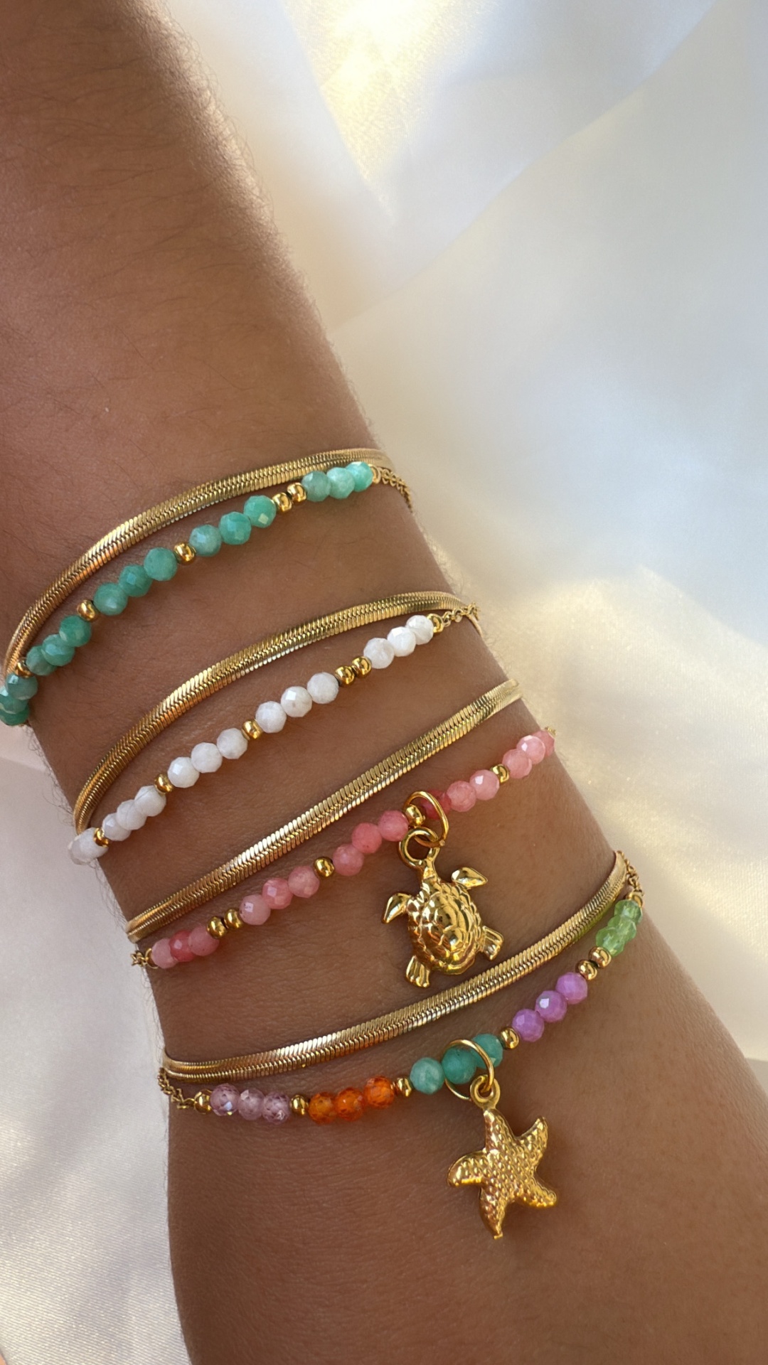 Pulseiras coloridas com pingentes de tartaruga e estrela do mar num pulso