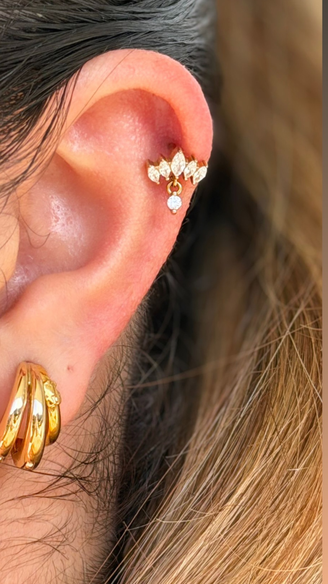 Piercing e brincos dourados com pedras em orelha