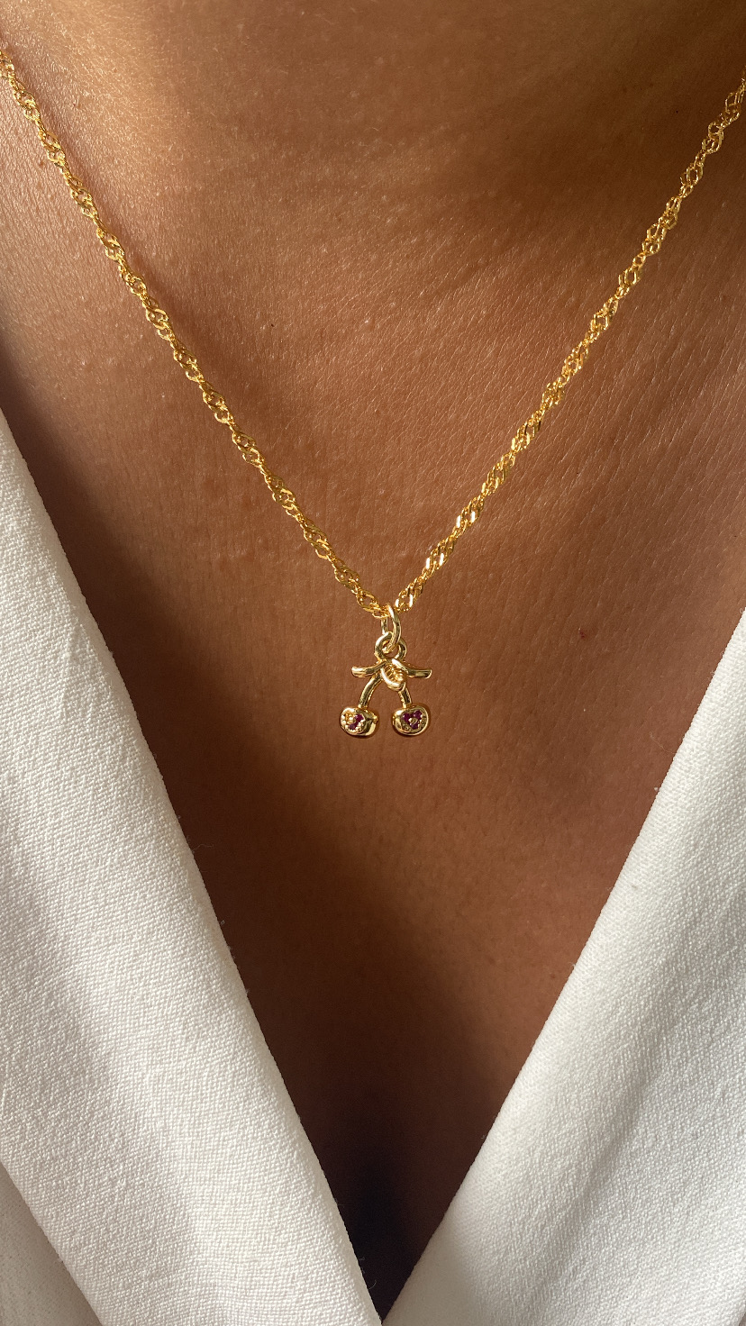 Colar dourado com pendente de cerejas cor-de-rosa