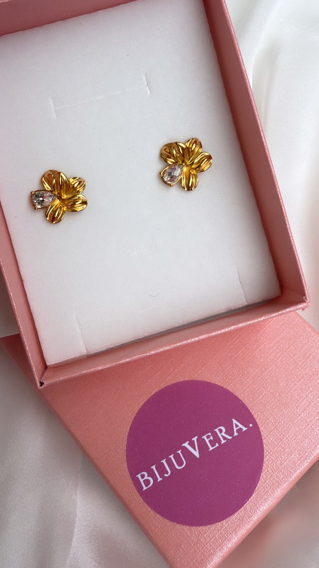 Brincos dourados florais com pedra clara em caixa rosa da BIJUVERA