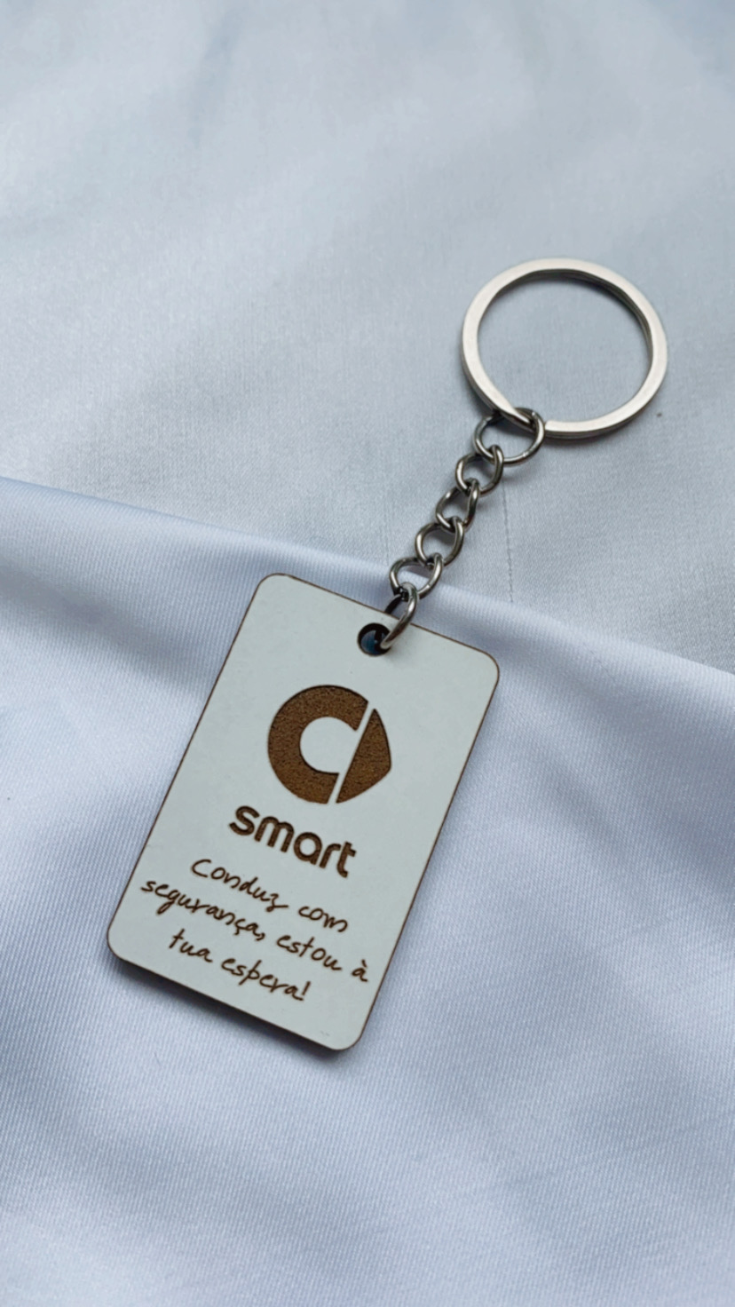 Porta-chaves branco retangular com texto e logotipo castanhos sobre tecido branco