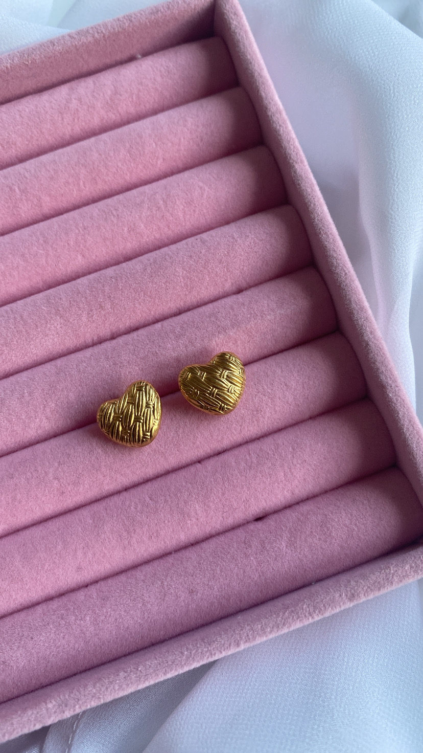 brincos dourados em forma de coração numa caixa de veludo rosa