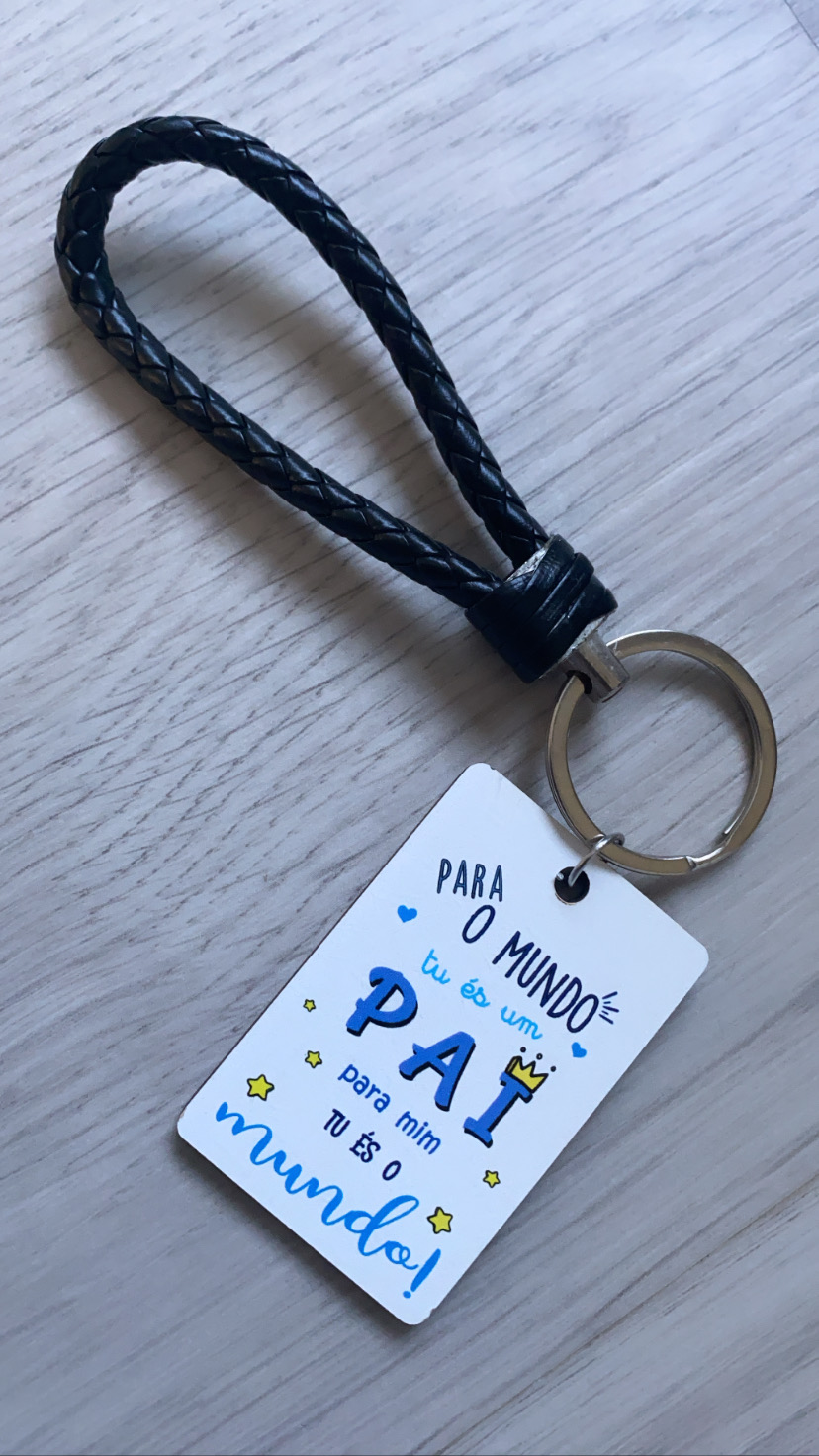 Porta-chaves com cordão trançado preto e pendente branco com texto em português e gráficos coloridos