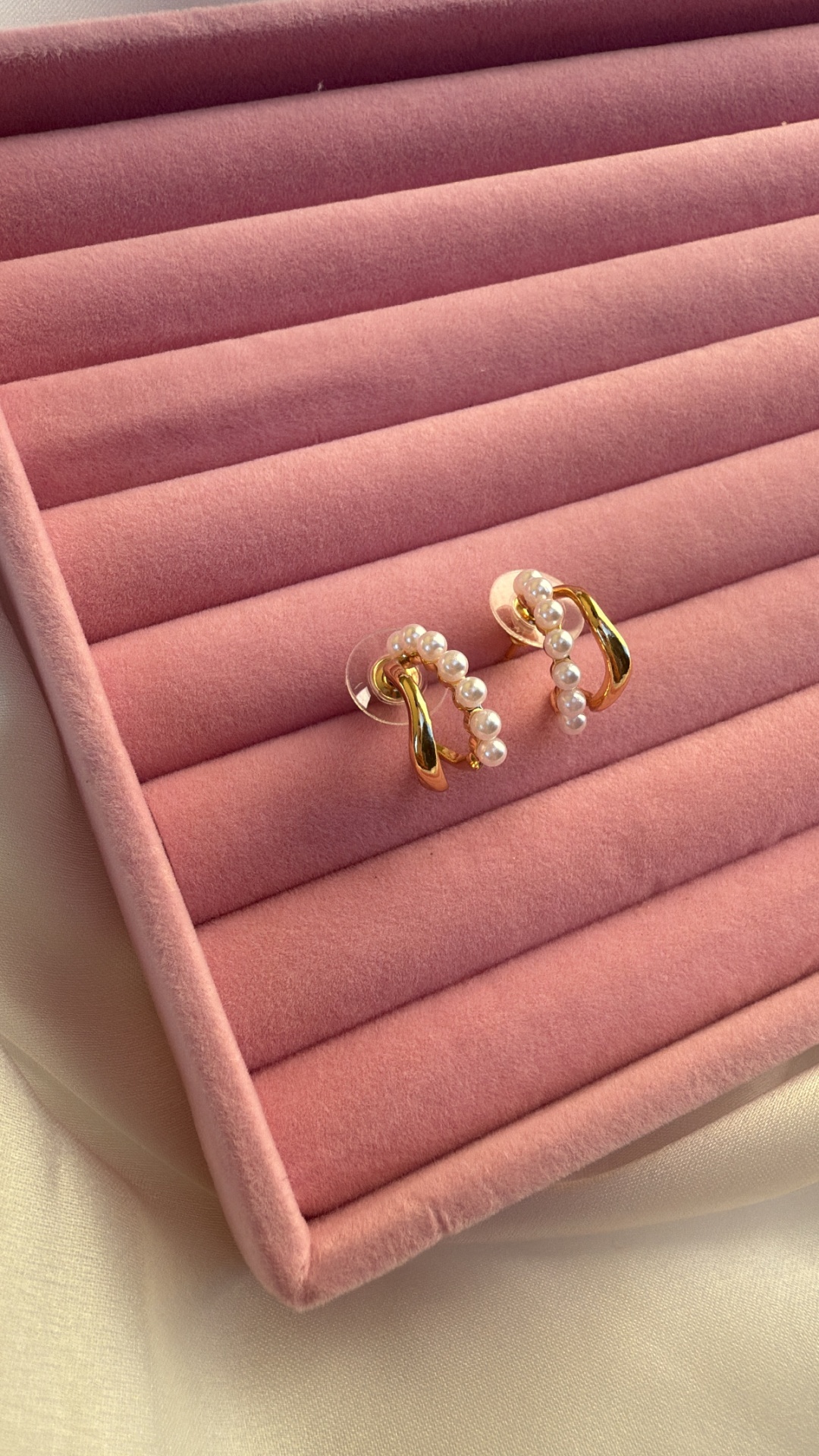Brincos dourados com pérolas numa caixa de veludo cor-de-rosa