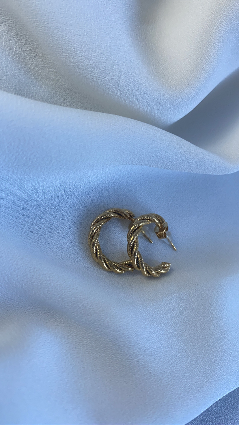 Brincos de argola dourados torcidos sobre tecido branco