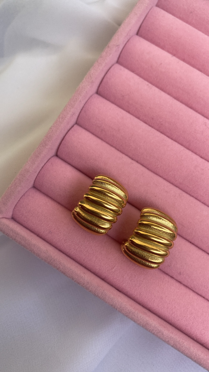 brincos dourados em almofada rosa de veludo