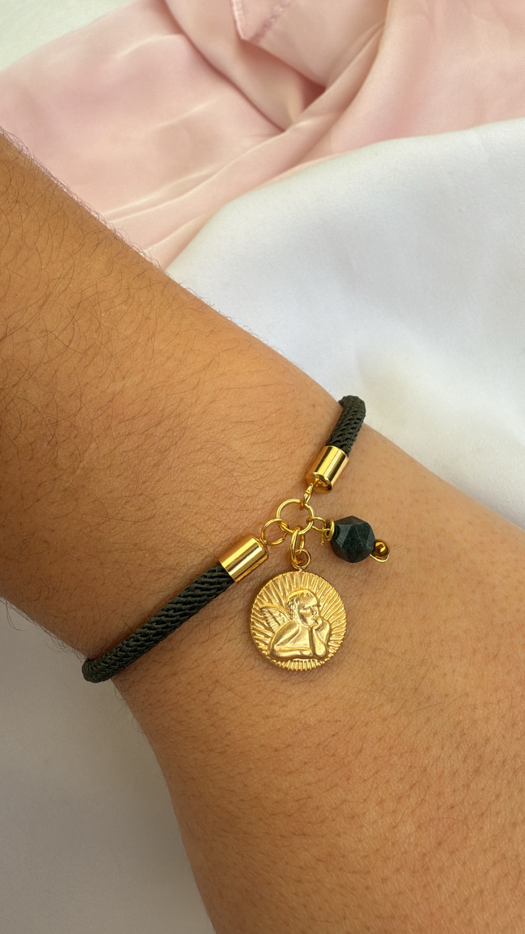 Pulseira preta com pendentes dourados e conta preta no pulso