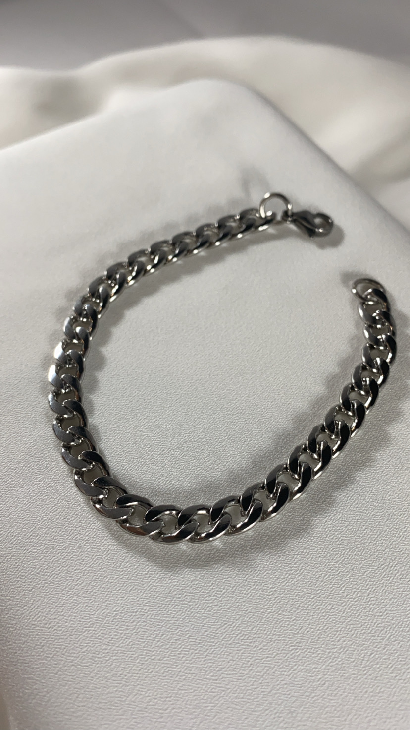 Pulseira de corrente grossa prateada sobre tecido branco