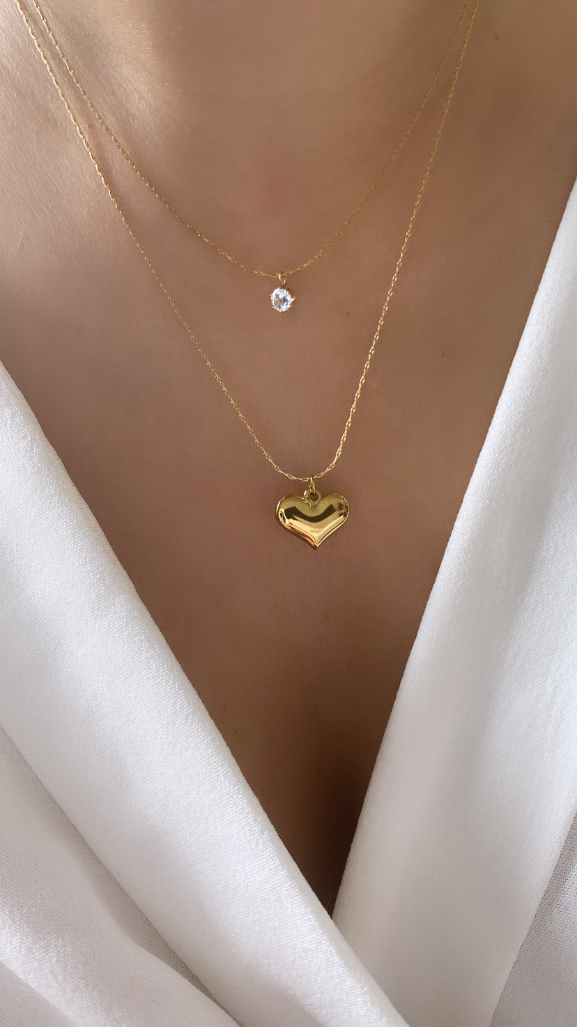 Colar duplo dourado com pedra e coração usado com roupa branca