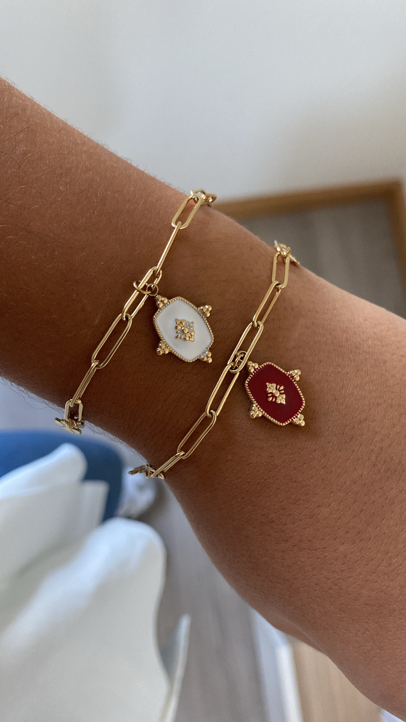 Pulseiras douradas com pendentes em esmalte branco e vermelho no pulso