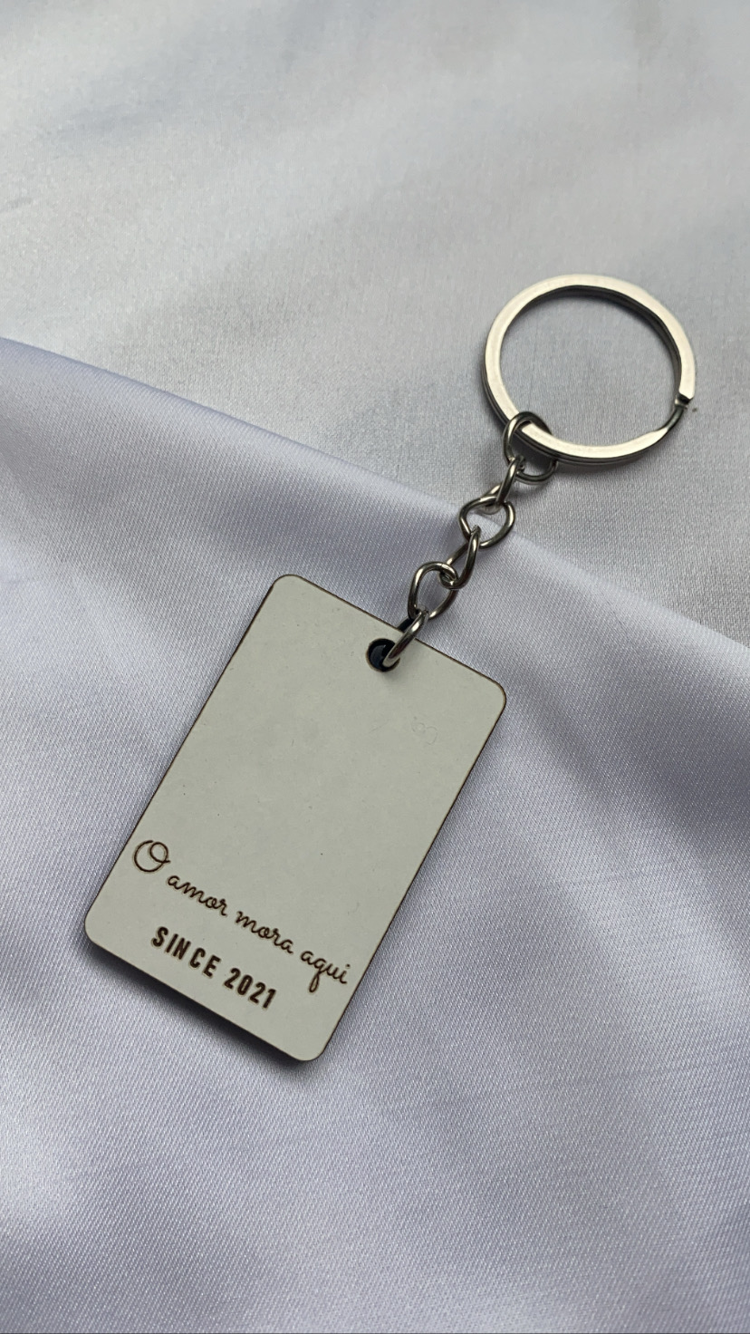 Chaveiro retangular branco com texto em castanho sobre tecido branco