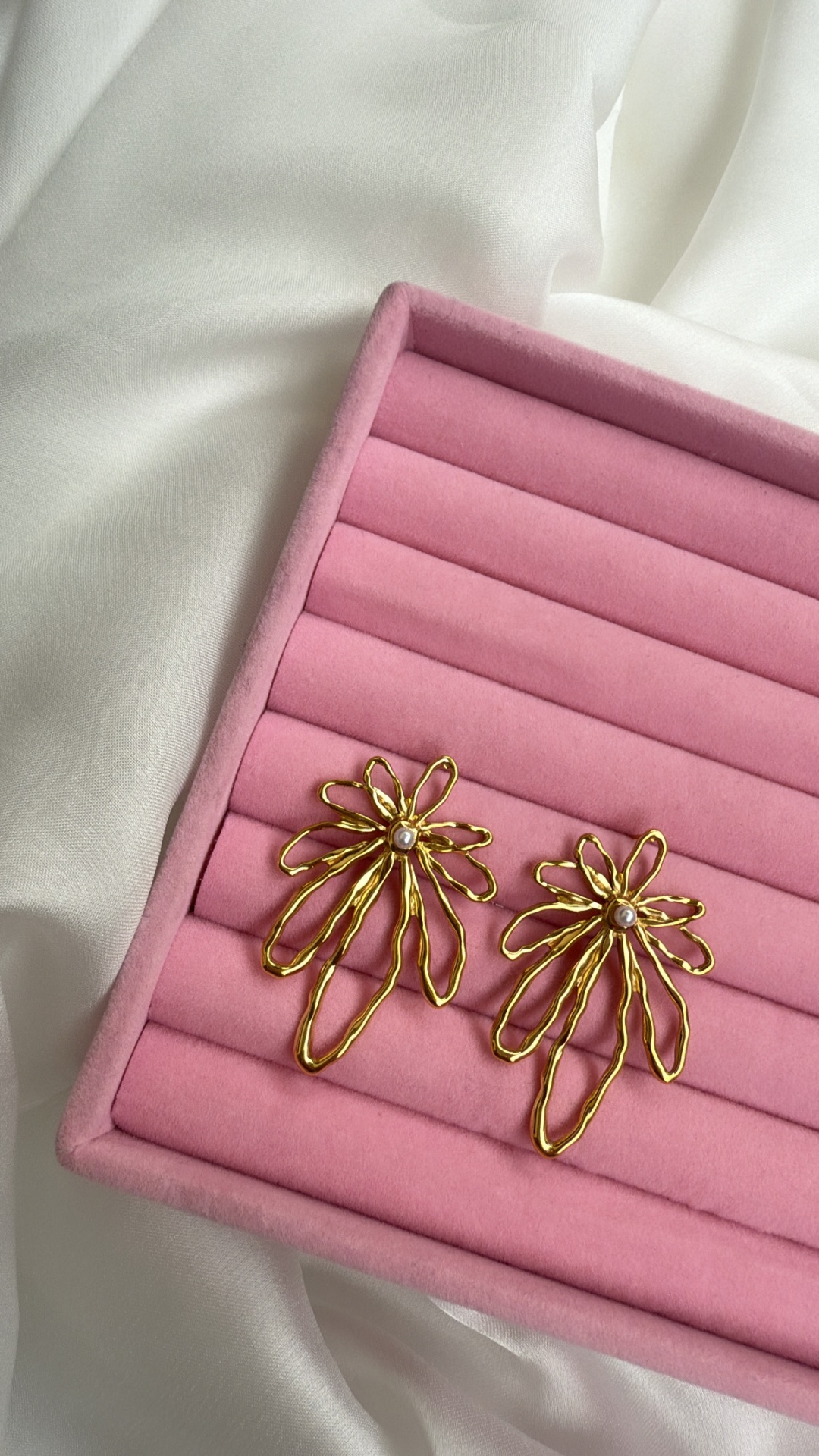 Brincos dourados em forma de flores com pérolas em caixa rosa
