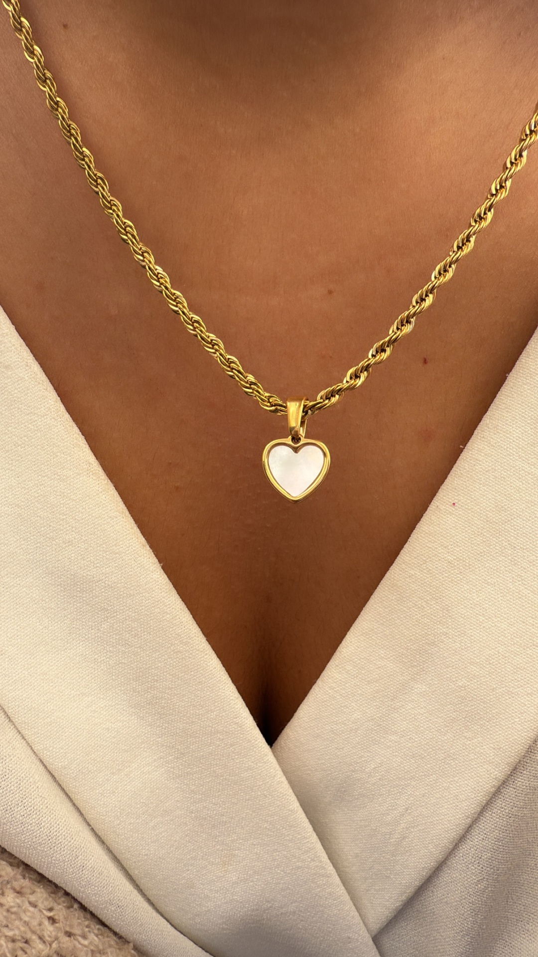 Colar dourado com coração branco ao pescoço