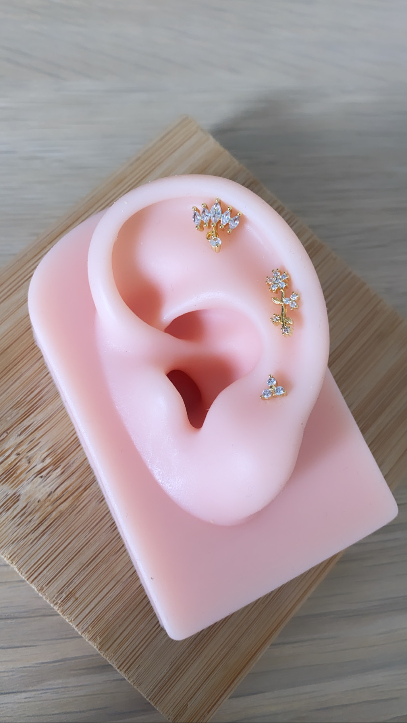 Modelo em silicone rosa de orelha com brincos dourados e pedras brilhantes