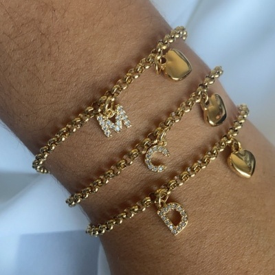 Três pulseiras douradas com letras e corações
