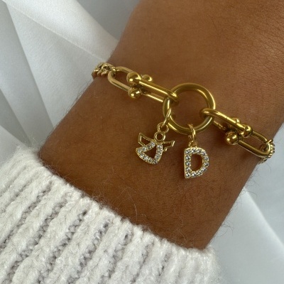 Pulseira dourada com pingentes de anjo e letra D em strass no pulso