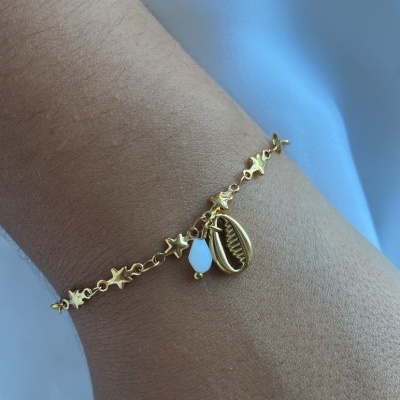 Pulseira dourada com estrelas e pendentes no pulso