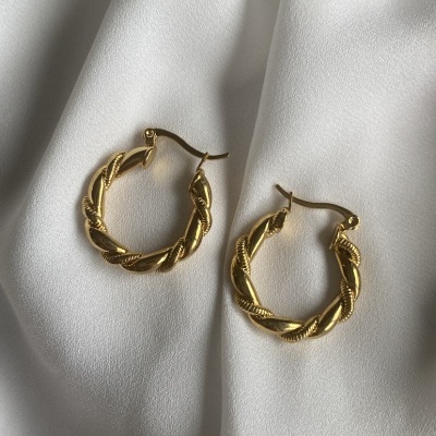 Brincos de argola dourados torcidos sobre tecido branco