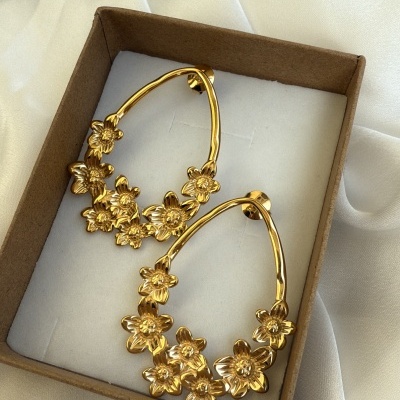 Brincos dourados com flores em caixa de cartão