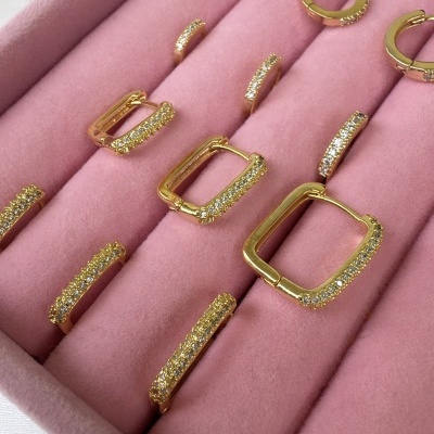 Conjunto de brincos dourados com pedras brilhantes em estojo rosa de veludo