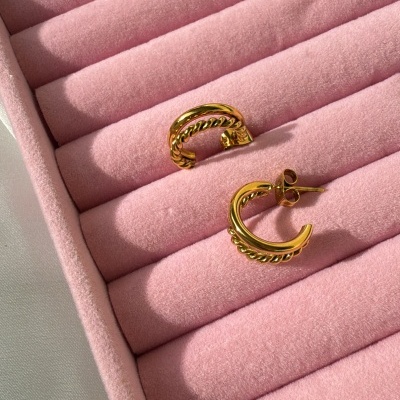 Par de brincos dourados com design de correntes numa caixa rosa acolchoada