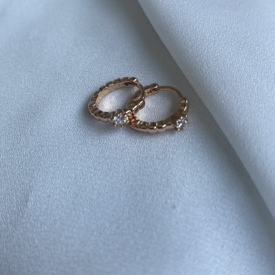 Brincos pequenos de argola dourados com pedras sobre tecido branco